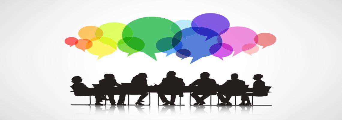 People sitting at a roundtable with multicolored speech bubbles above them